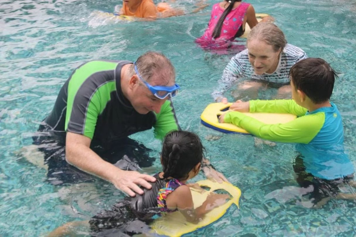 Voluntario enseñando natación a niños